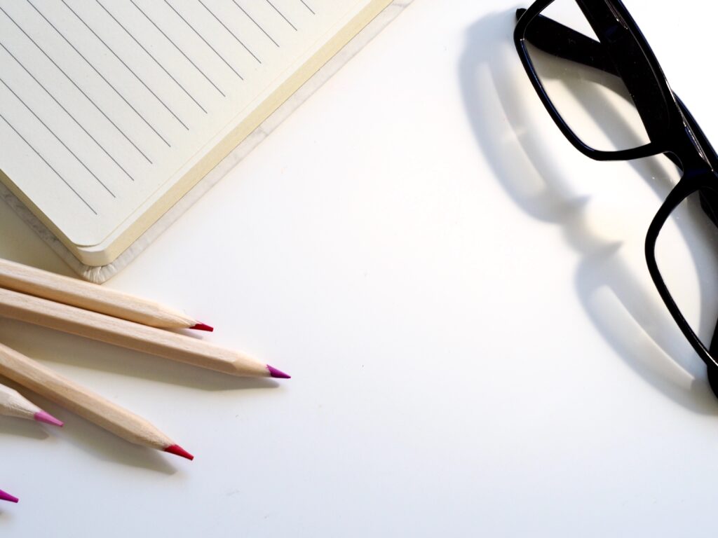 caderno, lápis e óculos para representar o plano de gestão escolar