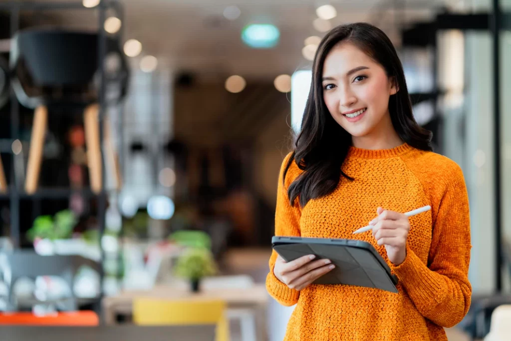 mulher asiática segurando tablet para ilustrar blogpost sobre departamento de marketing
